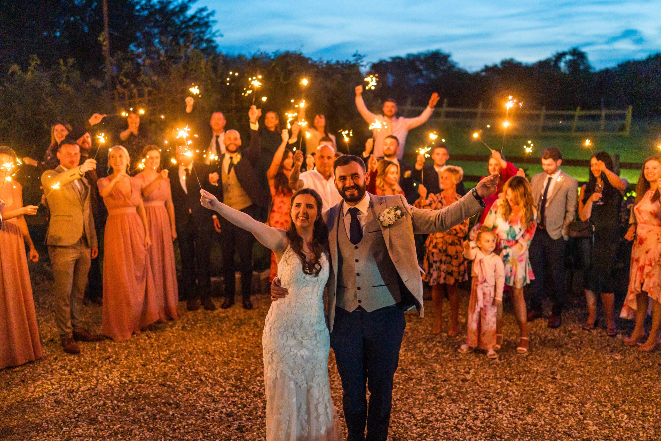 a couple and their guests enjoy a sparkler moment in the grounds of solton manor, dover, kent, england
