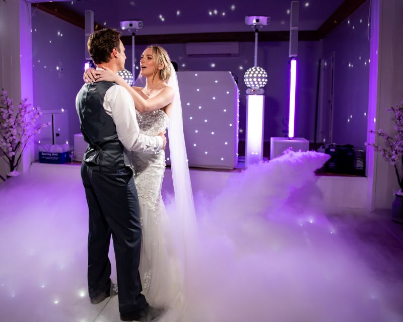 Newlyweds dancing in the Dutch Barn at Solton Manor, warm, rustic, draped barn wedding venue in Kent with twinkling lights and joyful atmosphere