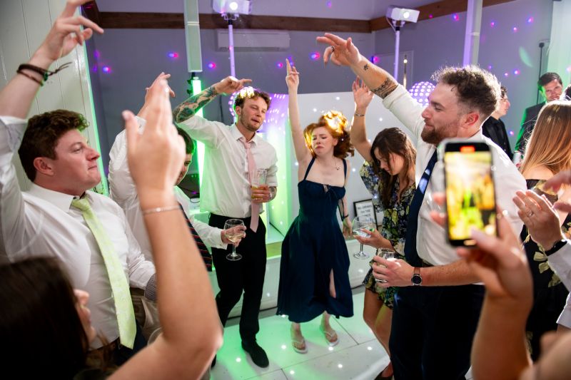 wedding guests dancing in the dutch barn at solton manor, a kent country manor wedding venue with rustic charm and lively evening receptions under twinkling lights