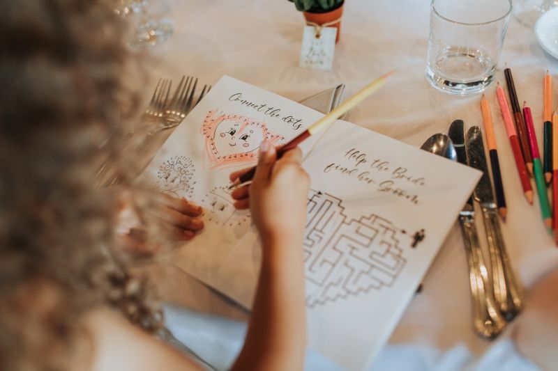 A young wedding guest has been given a colouring book during a wedding reception at Solton Manor, Near Canterbury, Kent, England