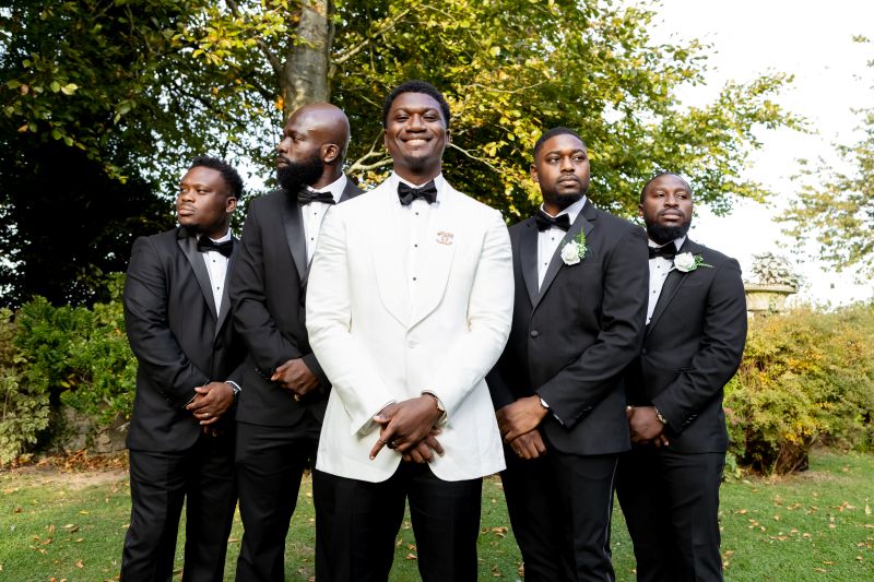 a groom at solton manor, wedding venue, with his groomsmen in the quintessential english garden
